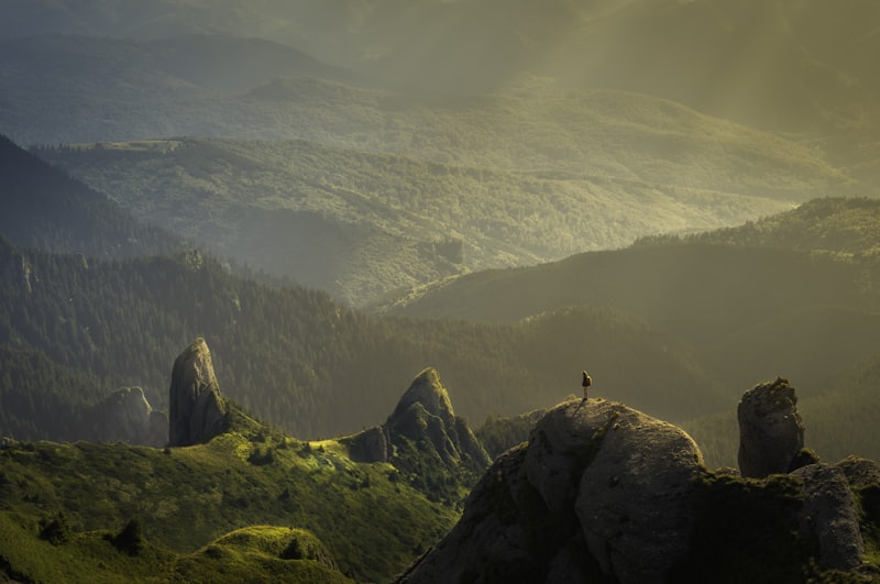 遠景の山の風景。岩の上に小さく人物が写っている